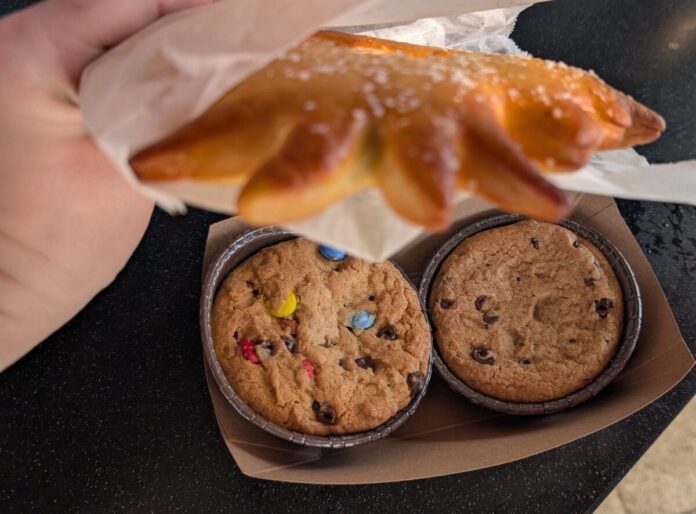 SeaWorld Orlando Christmas Food Guide 2025 A picture of a fresh baked deep-dish cookie and a wreath soft pretzel from the Christmas celebration at SeaWorld Orlando